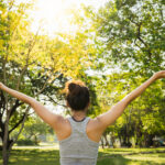 Healthy young Asian runner woman warm up the body stretching before exercise and yoga near lake at park under warm light morning. Lifestyle fitness and active women exercise in urban city concept.